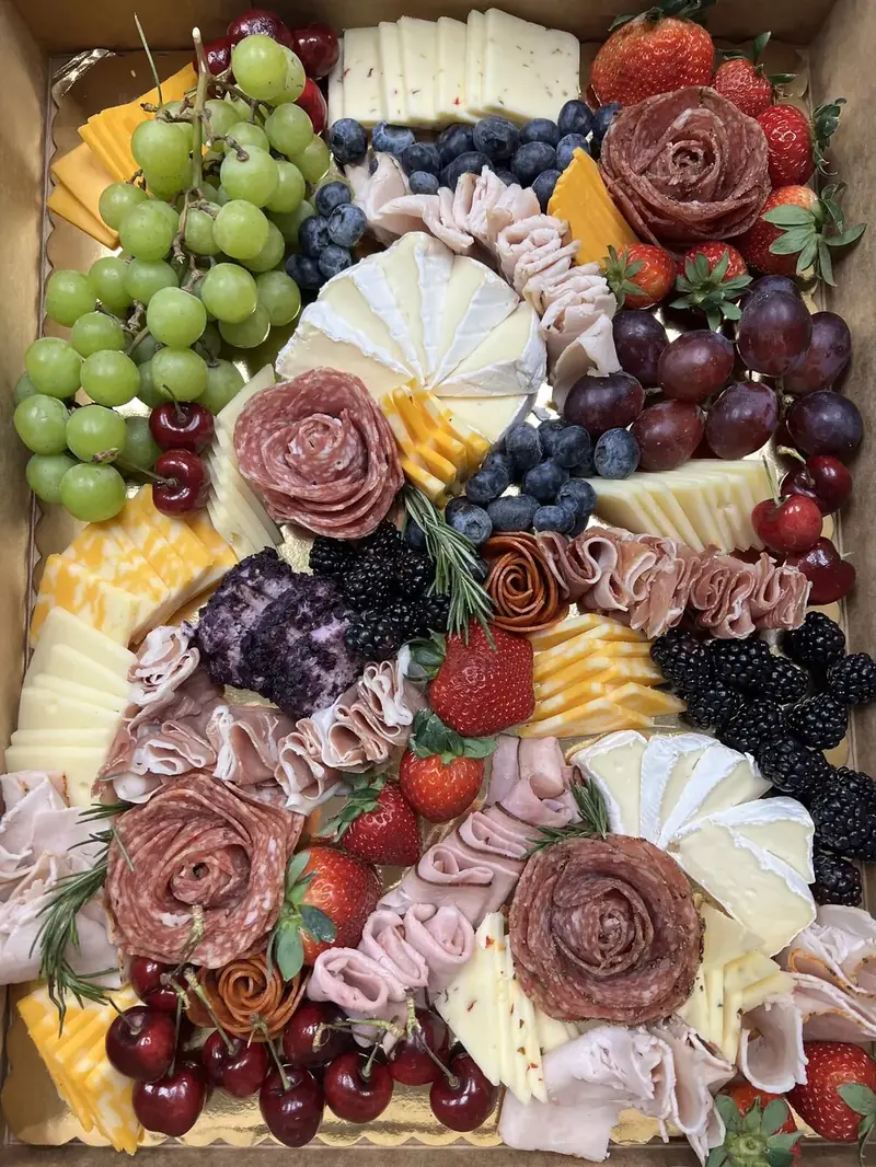 Large boxed charcuterie board with salami roses, cheeses, berries, cherries, and grapes catered by Lu's Cafe & Bakery