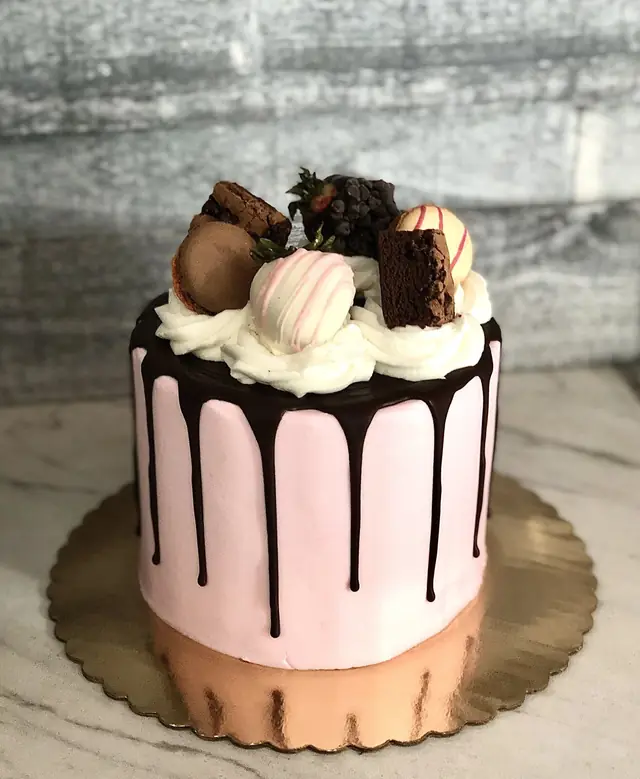 Pink chocolate drip cake with macarons and strawberries at Lu's
