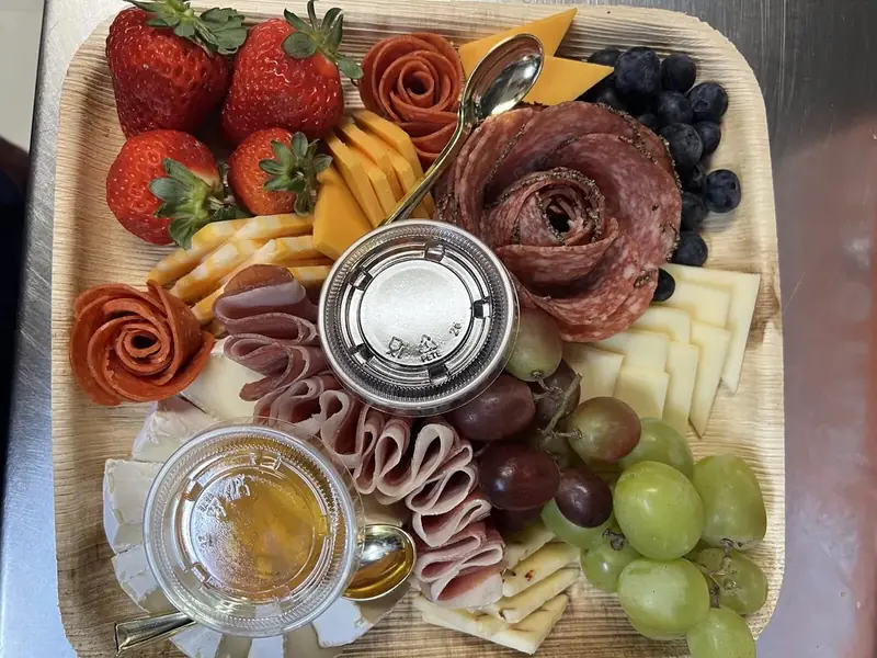 Charcuterie board with salami roses, cheeses, strawberries, grapes, and honey from Lu's Cafe & Bakery in Lawrence, MA