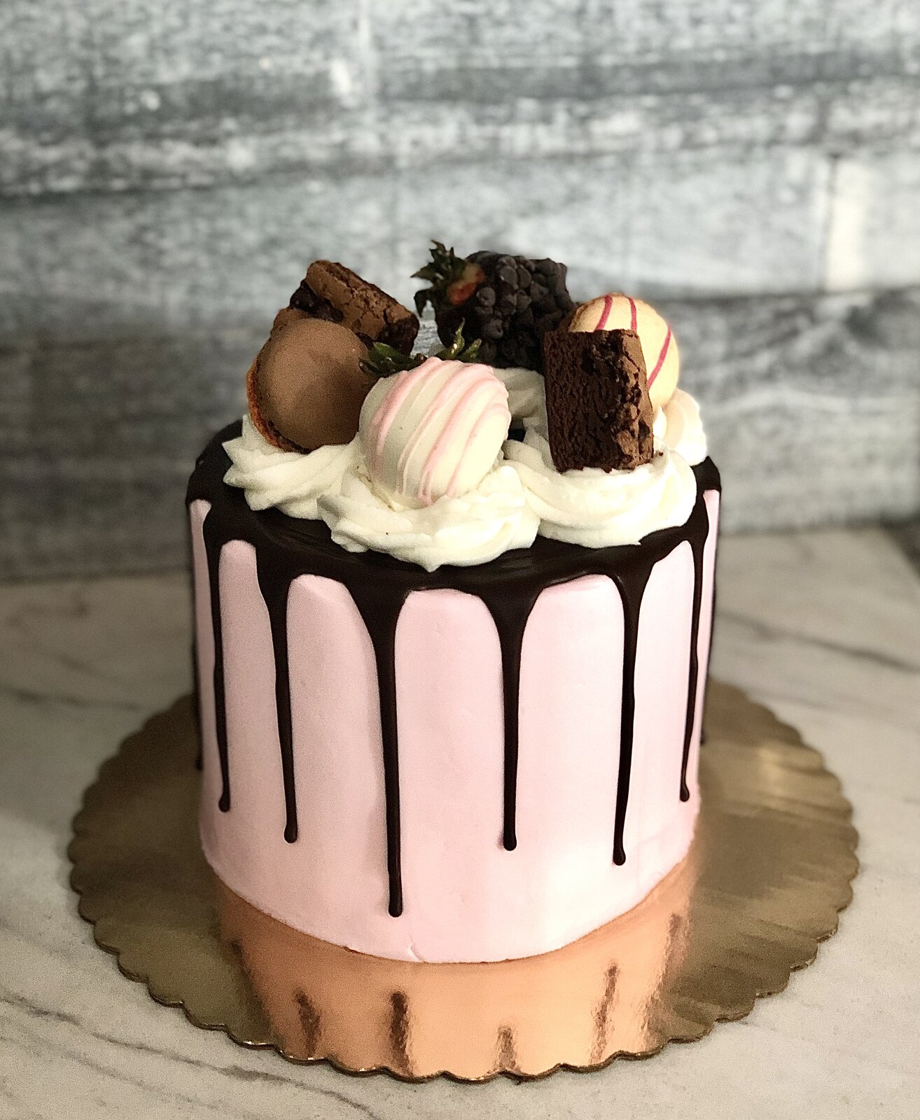 Pink chocolate drip cake with macarons and strawberries at Lu's